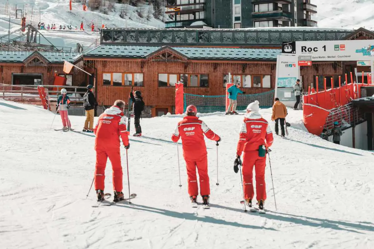 3 ski instructors are wearing there red outfits, an easy way to know they come from the most popular French Ski School ESF (École de Ski Français). Photo by Yann Allegre from Unsplash