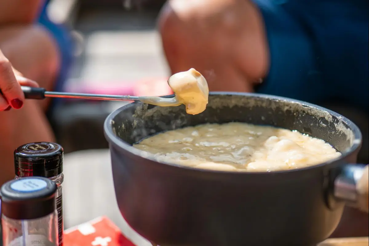 Dipping Bread Into A Traditional Cheese Fondue. Photo By Andri Aeschlimann, Unsplash