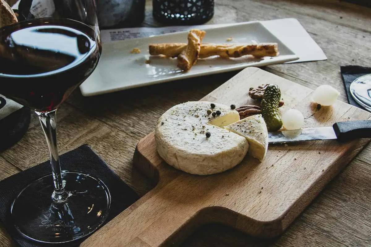 Selection of Swiss cheese and snacks on a platter with a glass of red wine. Photo by Camille brodard from Unsplash