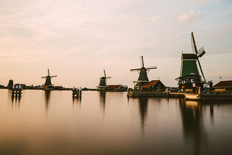 Moulins à vent néerlandais au bord de l'eau de De Zaanse Schans, près d'Amsterdam. Photo par Moritz Kindler, Unsplash.