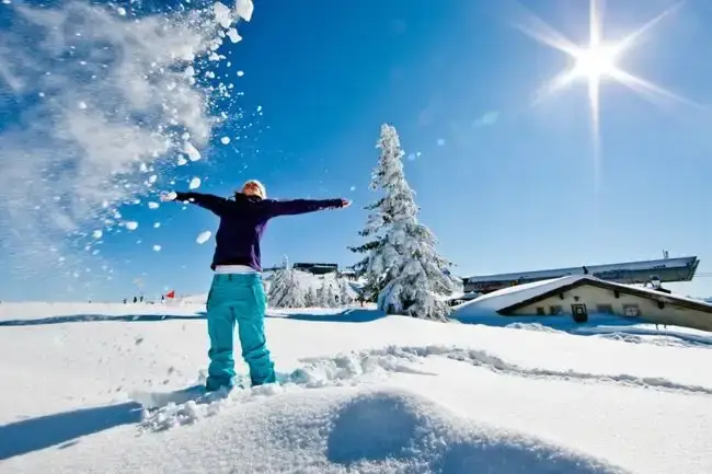 Mädchen in Skikleidung wirft mit Schnee um sich