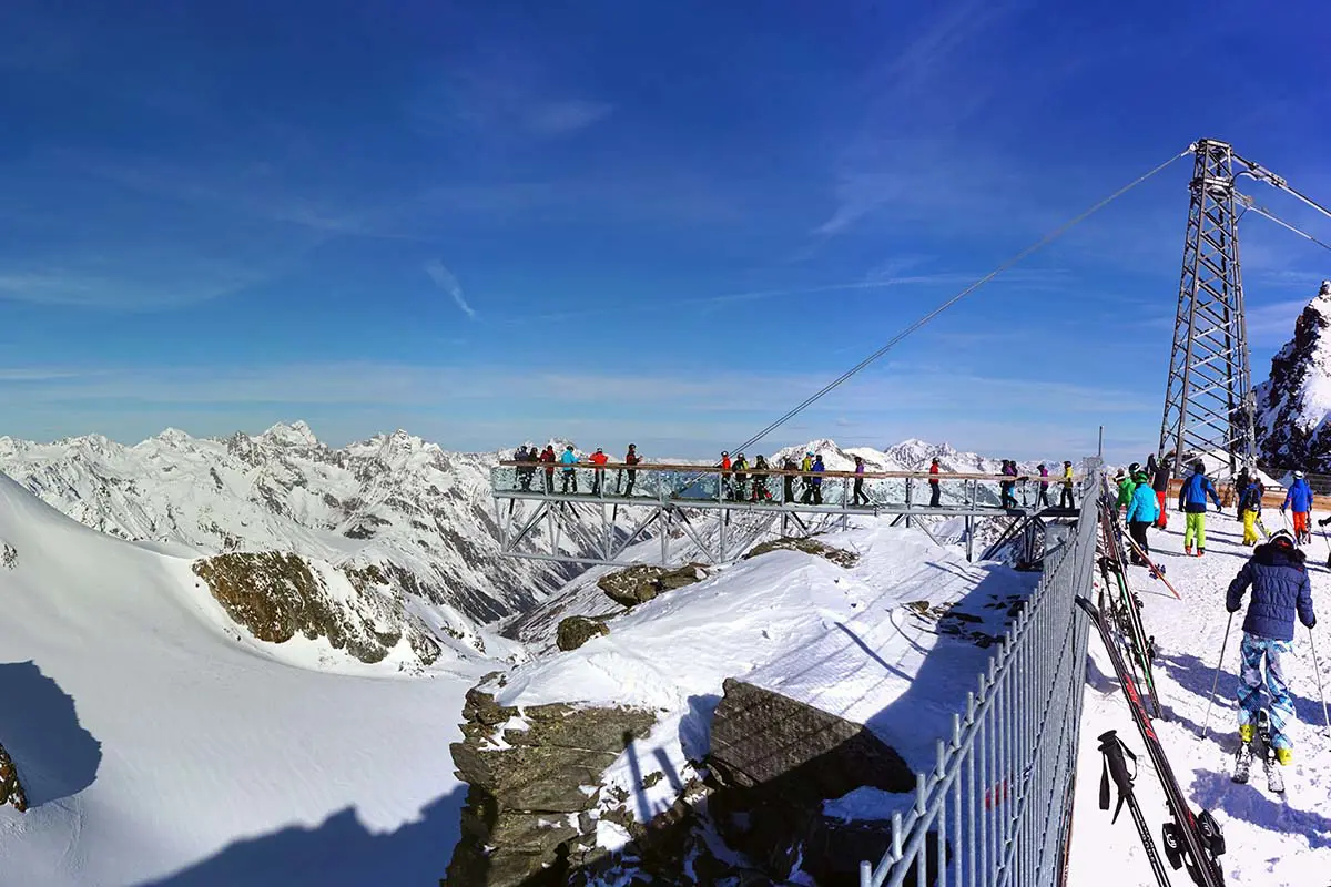 Viewing Platform With Skiers and Snow Covered Mountains in Solden, Austria. Photo by Nervosa22, Pixabay.