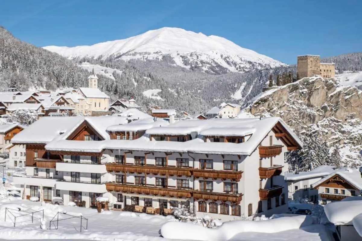 Hotel Puint, umgeben von schneebedeckten Bergen und klarem blauem Himmel, St. Anton, Österreich.