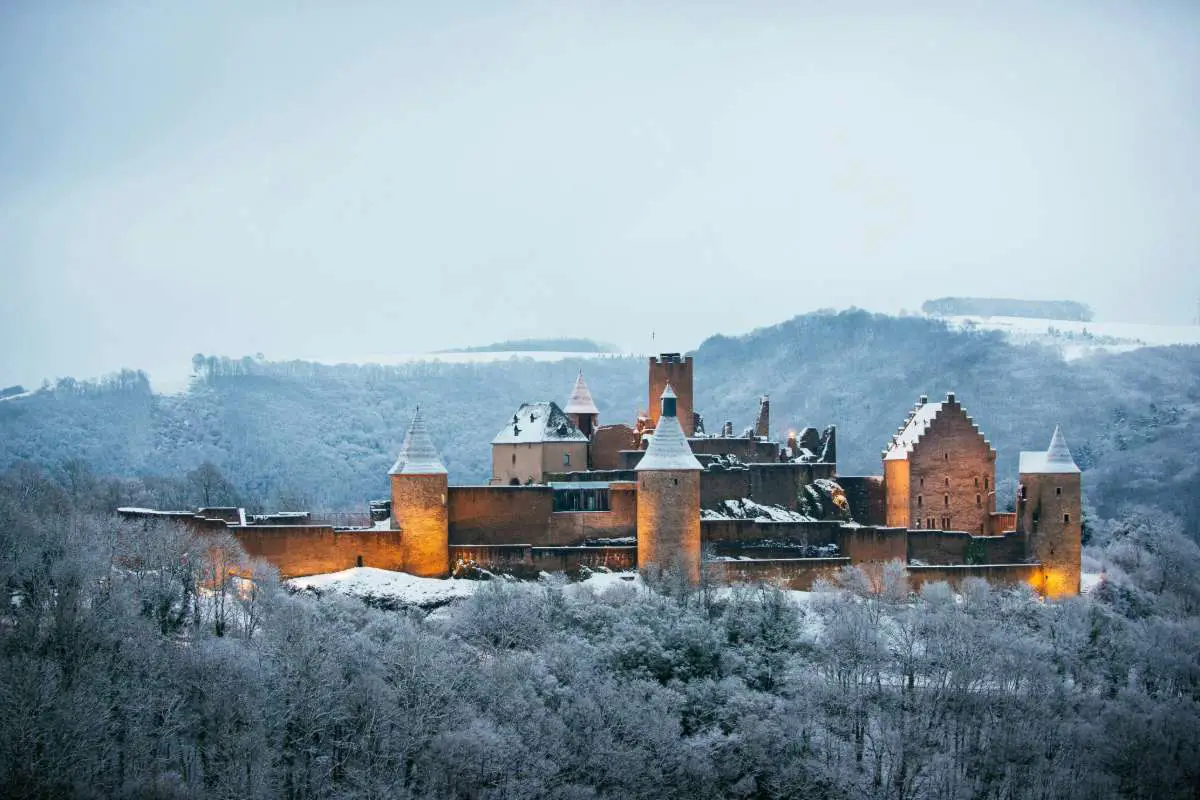Bourscheid Castle in Luxembourg illuminated and covered in snow. Photo by Marc Marchal from Unsplash