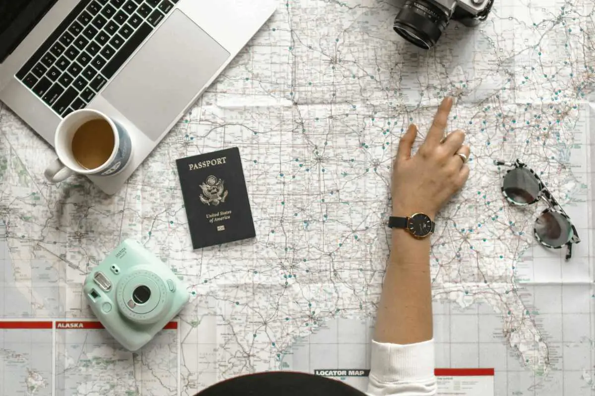 Trip planning with cameras, passport and laptop on a map. Photo by Element 5 Digital from Unsplash 