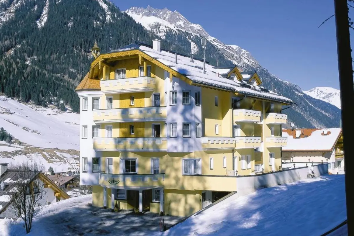 Vooraanzicht van Hotel Garni Waldschlössl in Ischgl, Oostenrijk, omringd door besneeuwde bergen.