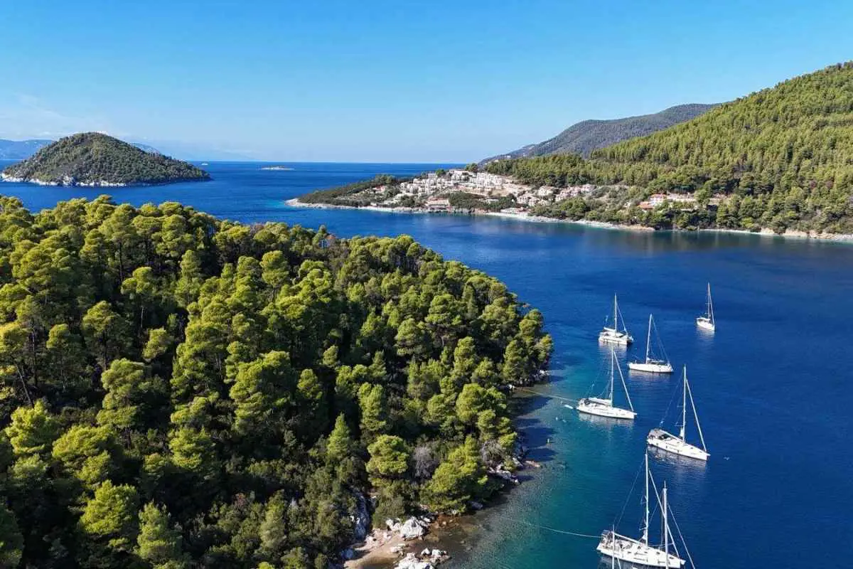 Six sailing boats anchored in a blue bay of a Greek Island.