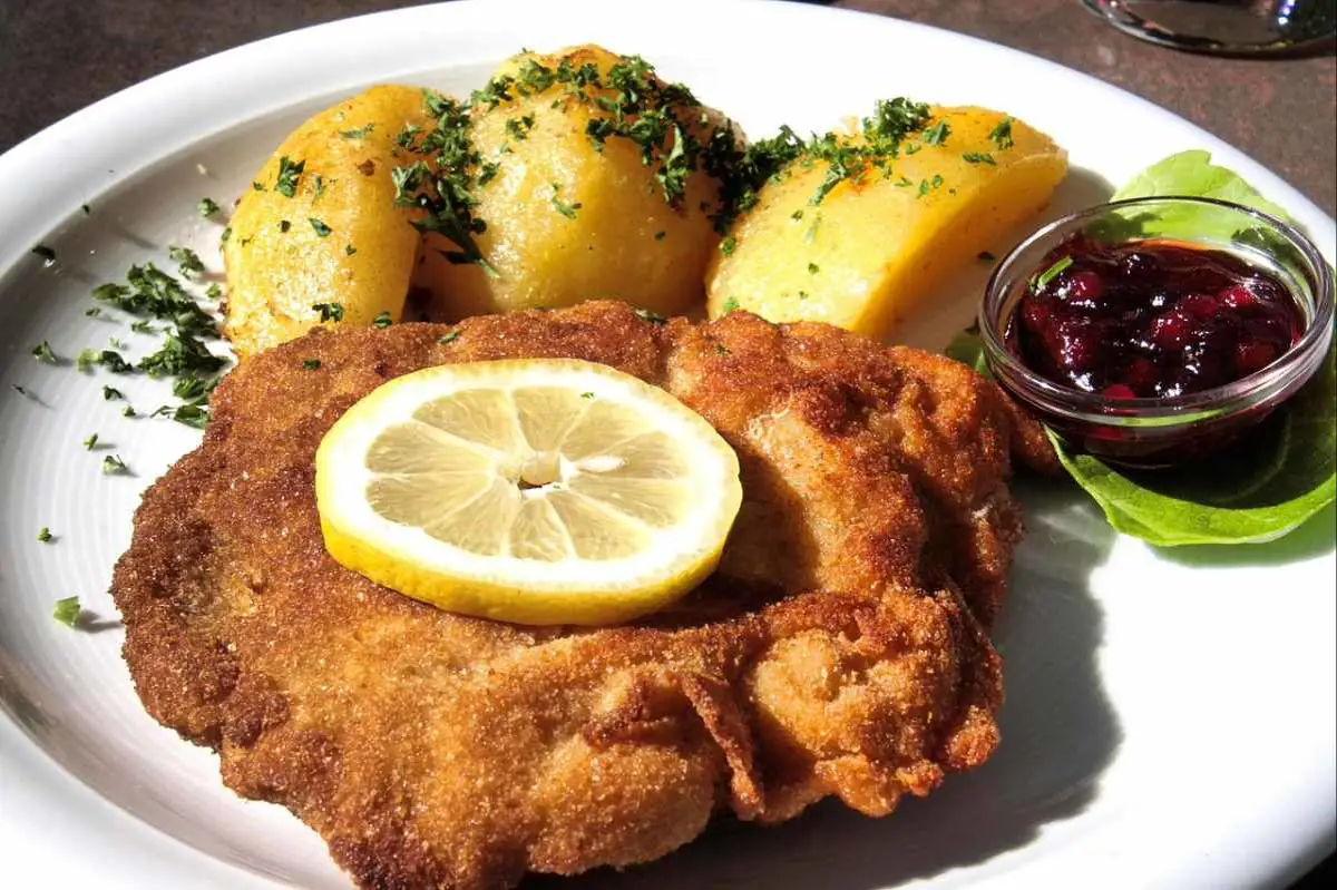 Traditional Austrian schnitzel on a plate garnished with potatoes and a fresh slice of lemon. Photo by Reinhard Thrainer from Pixabay