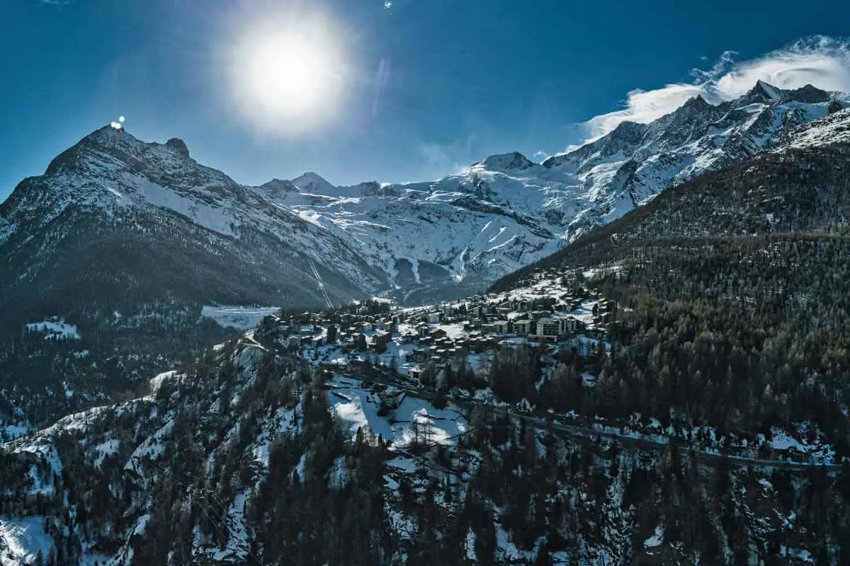 Drone photo of the Saas-Fee ski resort, Switzerland from above on a sunny day with snow capped mountains. Photo by Daniel R from Unsplash