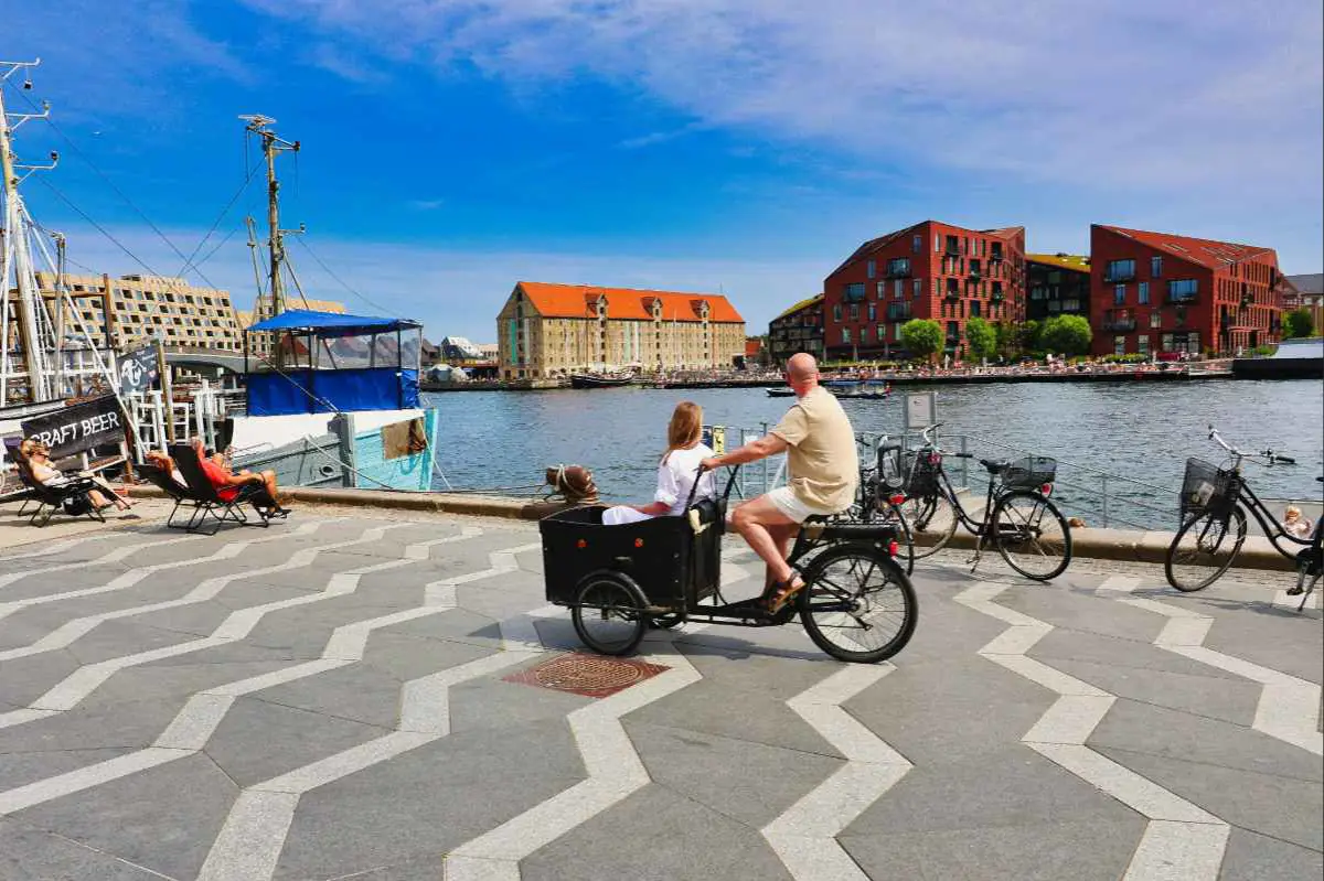 A couple cycling from Nyhavn along the northern Sydhavn canal to the Cykelanlangen cycle bridge, taking in the tranquil public spaces of Copenhagen. Photo by Alain Rouiller from Unsplash