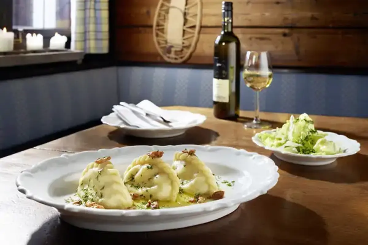 Restauranttafel met bord met Kaesnudel en fles witte wijn