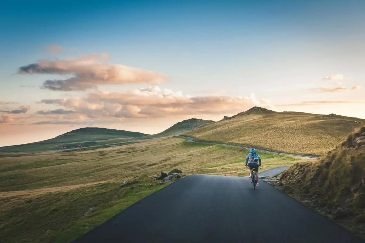 Holidaymaker cycling in the green hills of Piatra Arsă, Romania. Photo by Urban Vintage from Unsplash.