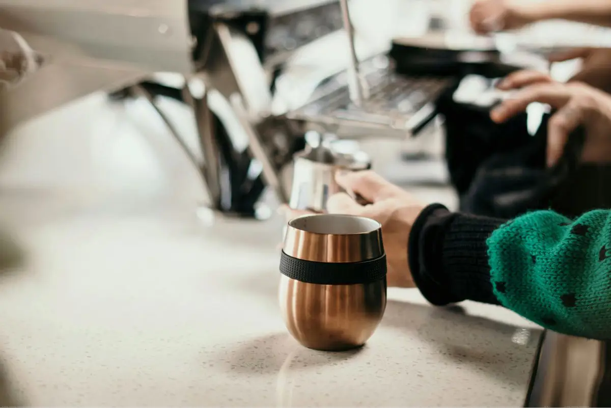 CAFE CONCETTO Tumbler being filled at a coffee shop by a barista. Photo by cafe concetto from Unsplash 
