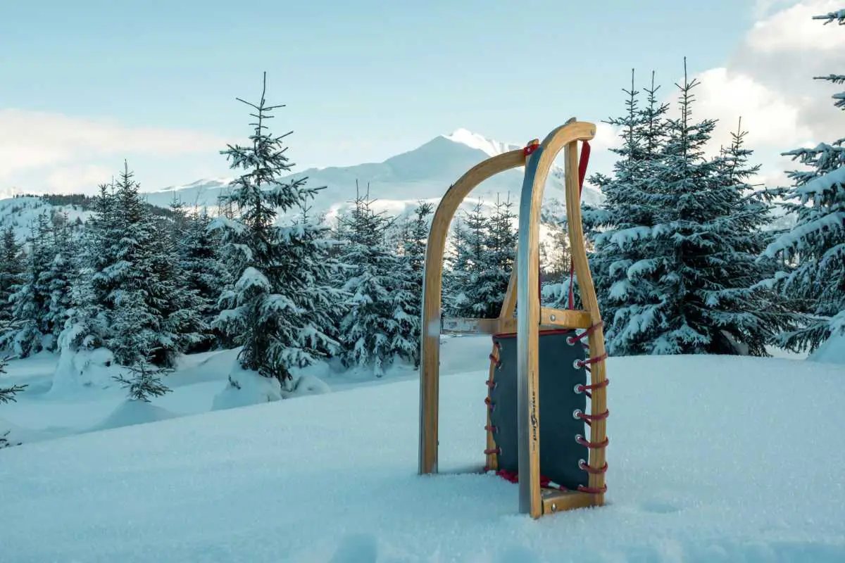 Traditional wooden sledge standing up in the snow on a calm day in Feldis, Domleschg, Switzerland. Photo by Patrick Robert Doyle from Unsplash