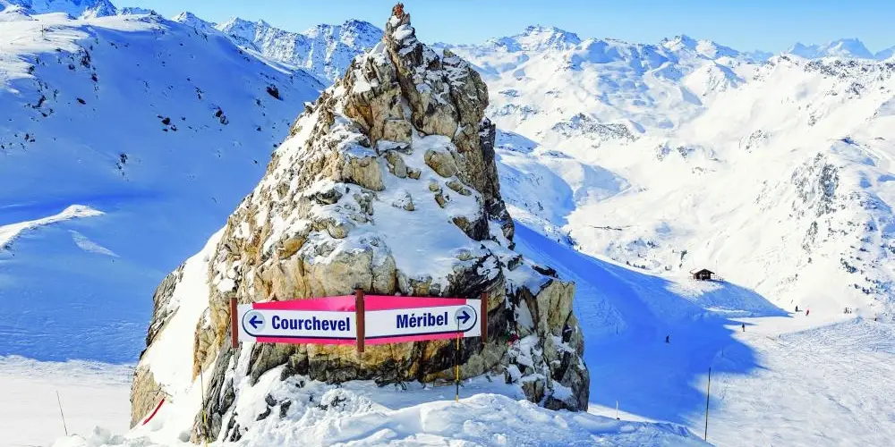 Two Traffic Sign Banners Against a Snowy Rock Directing to Courchevel and Meribel France