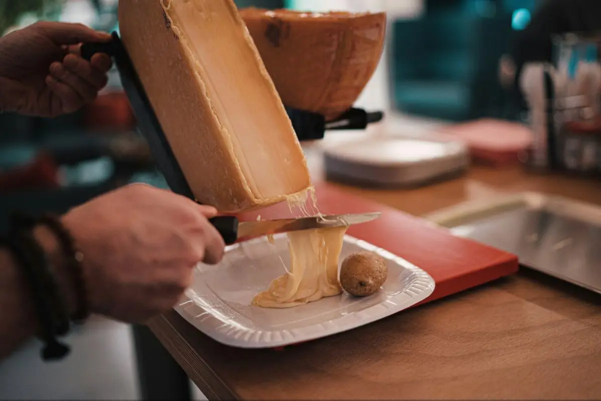 Traditional raclette cheese being drizzled over a plat for potatoes in Switzerland. Photo by Claudio Schwarz from Unsplash