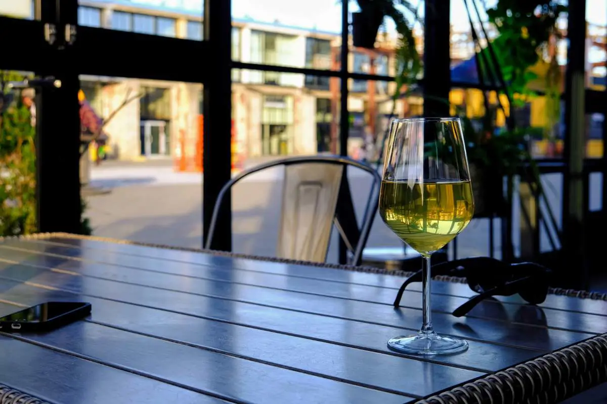 Glass of white wine on a table in Nudist Winery in Tallinn's Telliskivi Creative City, Estonia. Photo by Mirko Bozic from Unsplash