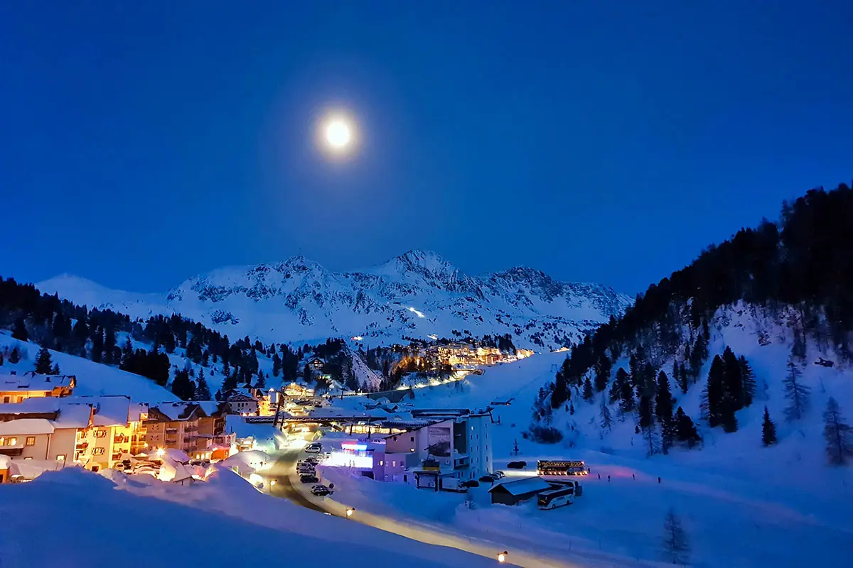 Snowy Mountain Village bei Nacht mit Vollmond in Obertauern, Österreich. Foto von Digitalarbyter, Unsplash.