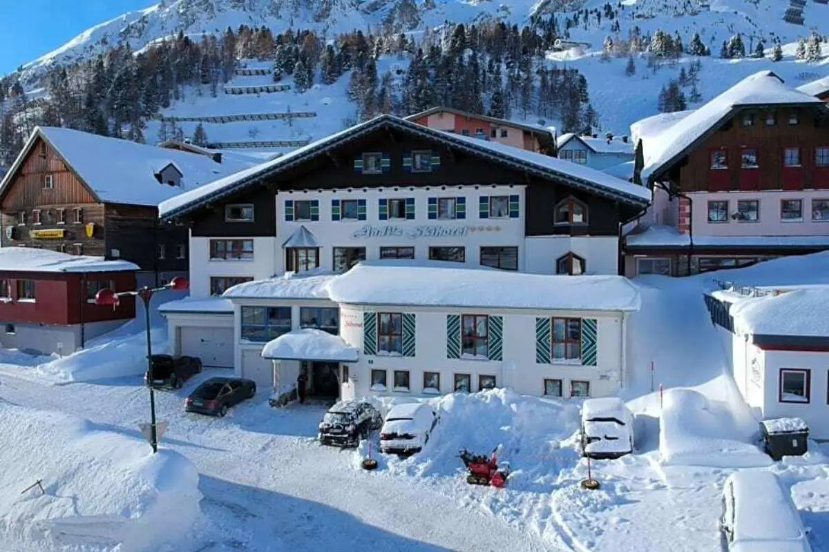 Vorderansicht von Andis Skihotel, das vor einer von Bäumen gesäumten Bergkulisse in Obertauern, Österreich, in Schnee gehüllt ist.